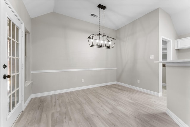 unfurnished dining area with light wood-type flooring, vaulted ceiling, and a notable chandelier