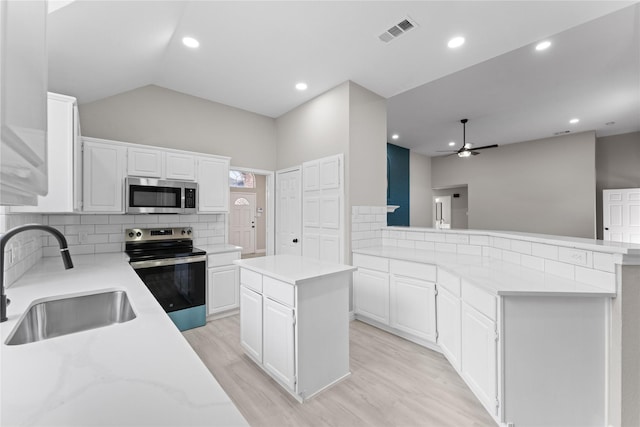 kitchen featuring a center island, tasteful backsplash, white cabinets, appliances with stainless steel finishes, and sink