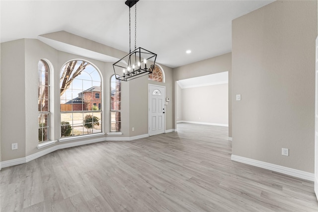 unfurnished dining area with light hardwood / wood-style floors, plenty of natural light, and a notable chandelier