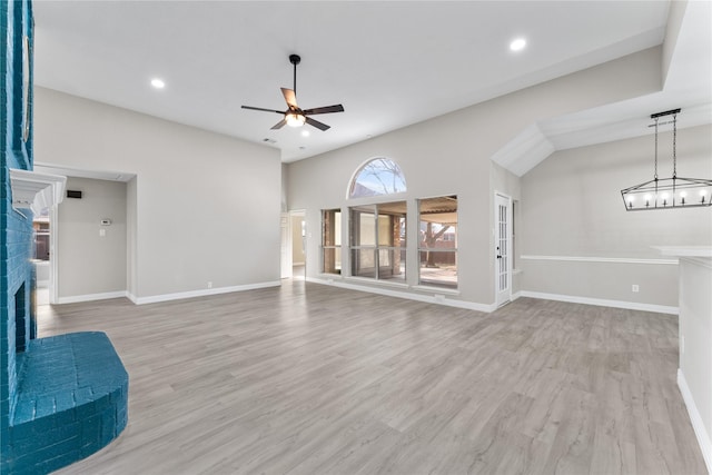 living room featuring light hardwood / wood-style floors, a brick fireplace, and ceiling fan with notable chandelier