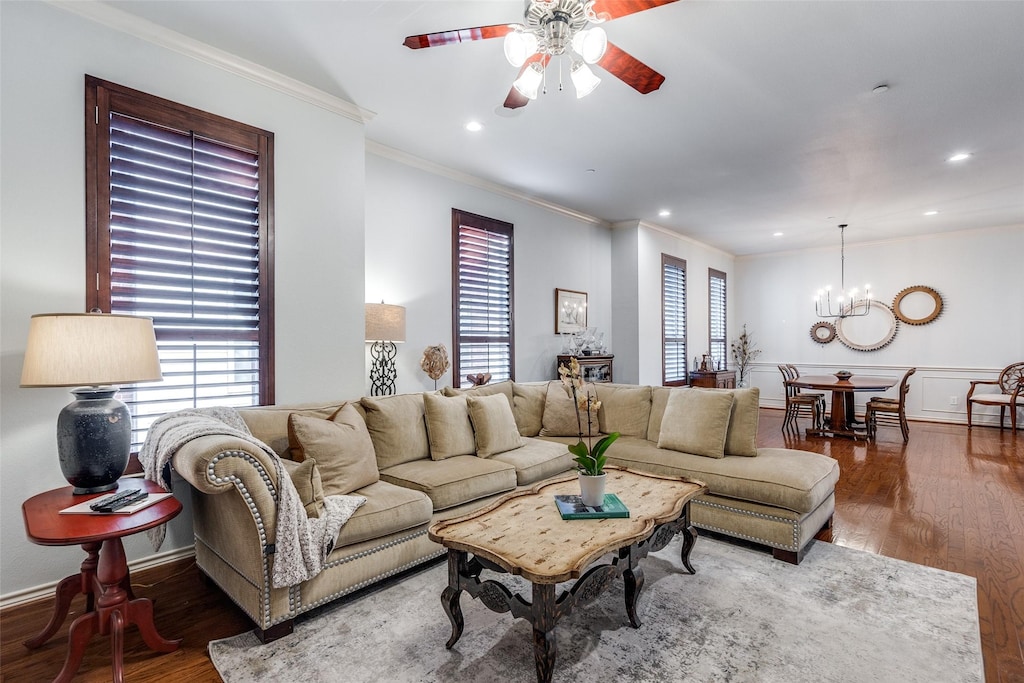 living room featuring ceiling fan with notable chandelier, crown molding, and dark hardwood / wood-style flooring