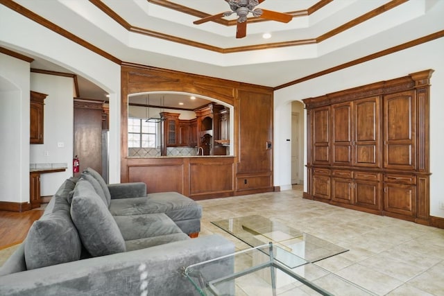 living room featuring a raised ceiling, ceiling fan, and crown molding