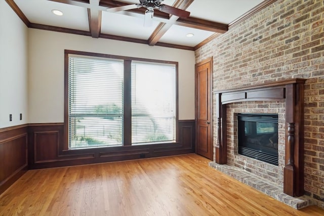 unfurnished living room with coffered ceiling, light wood-type flooring, beamed ceiling, ornamental molding, and a fireplace