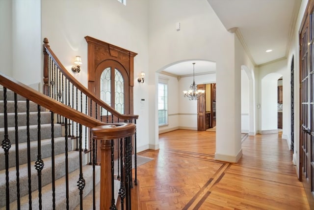 foyer featuring a high ceiling, ornamental molding, and a chandelier