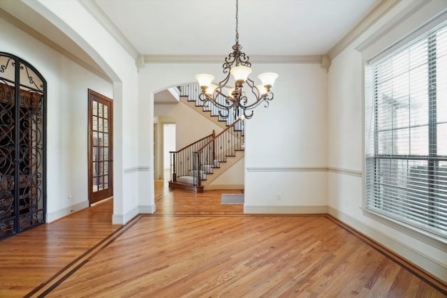 unfurnished dining area featuring an inviting chandelier, hardwood / wood-style floors, and crown molding