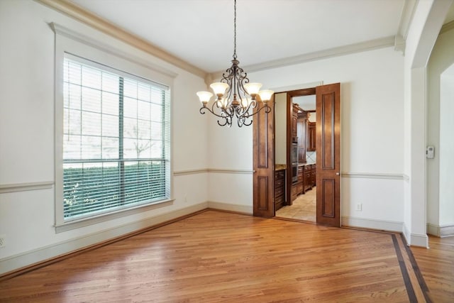 unfurnished dining area with a notable chandelier, light hardwood / wood-style floors, and ornamental molding