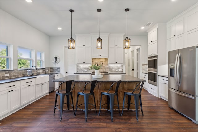 kitchen featuring stainless steel appliances, white cabinetry, and hanging light fixtures