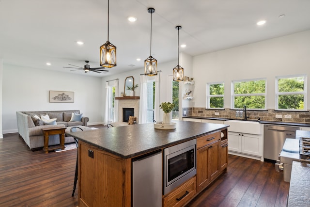 kitchen with dark hardwood / wood-style floors, hanging light fixtures, stainless steel appliances, a kitchen island, and white cabinets