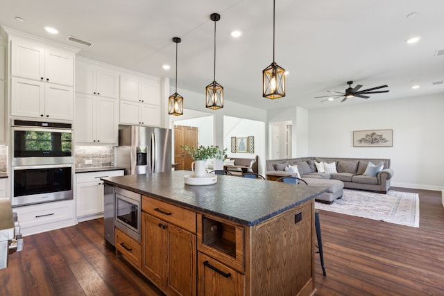 kitchen with a kitchen island, white cabinets, appliances with stainless steel finishes, and dark hardwood / wood-style floors