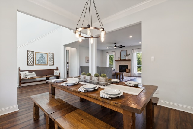 dining area featuring dark wood-type flooring, crown molding, and ceiling fan with notable chandelier