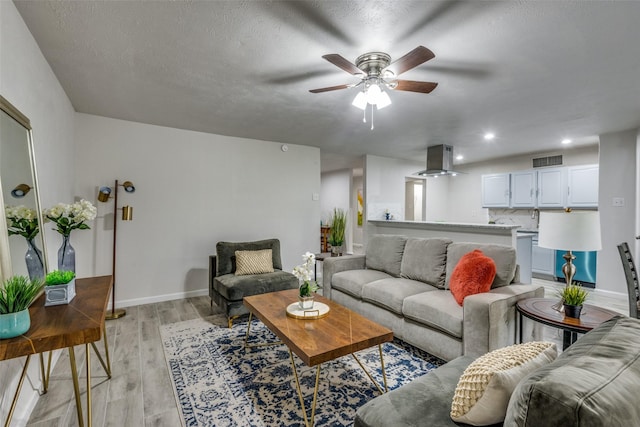 living room with light wood-type flooring, ceiling fan, and a textured ceiling