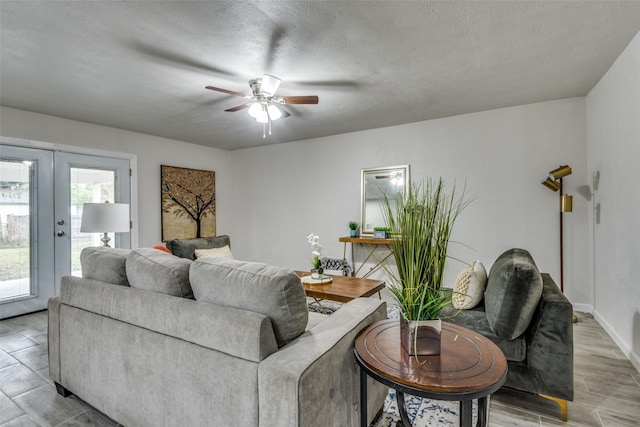 living room with light wood-type flooring, ceiling fan, french doors, and a textured ceiling