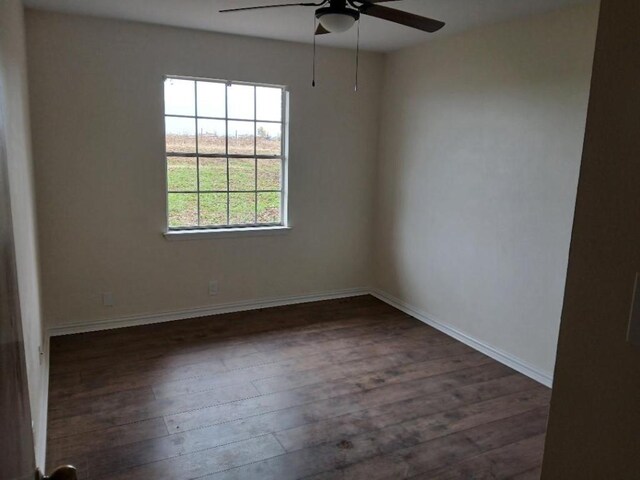 spare room with a ceiling fan, dark wood-style flooring, and baseboards
