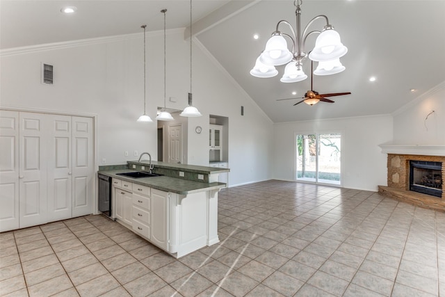 kitchen featuring sink, white cabinets, ceiling fan with notable chandelier, pendant lighting, and a stone fireplace