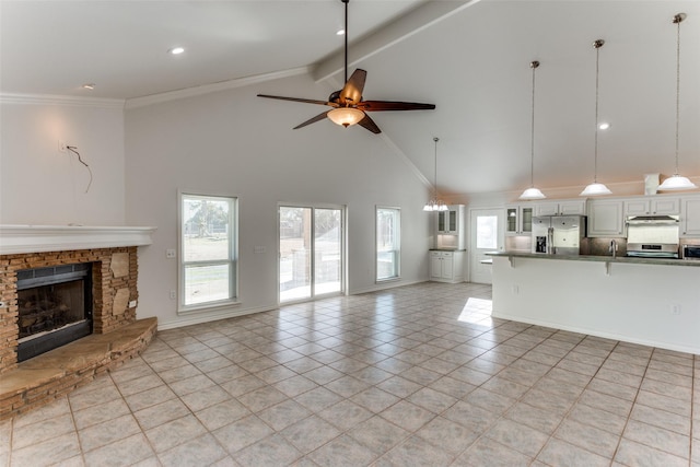 unfurnished living room with a fireplace, beamed ceiling, ornamental molding, ceiling fan, and light tile patterned floors