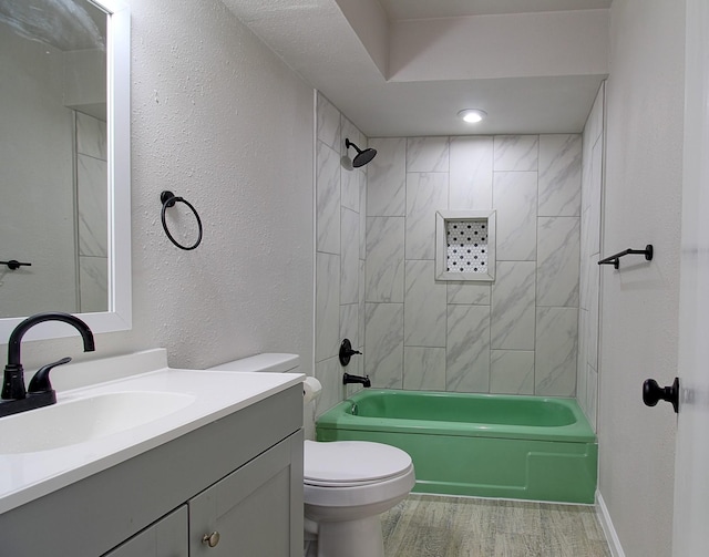 full bathroom featuring vanity, tiled shower / bath combo, and toilet