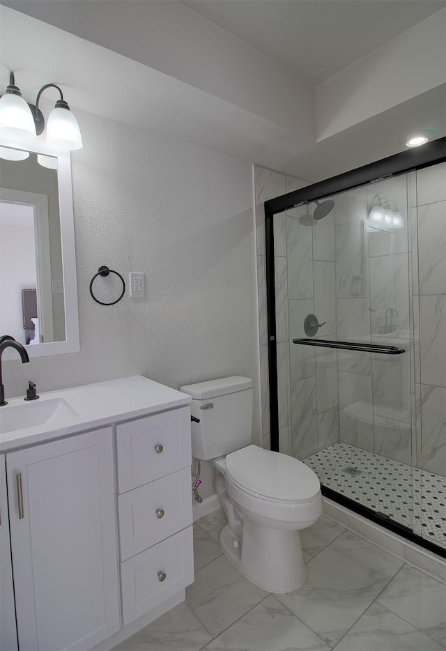 bathroom with toilet, vanity, and a shower with shower door