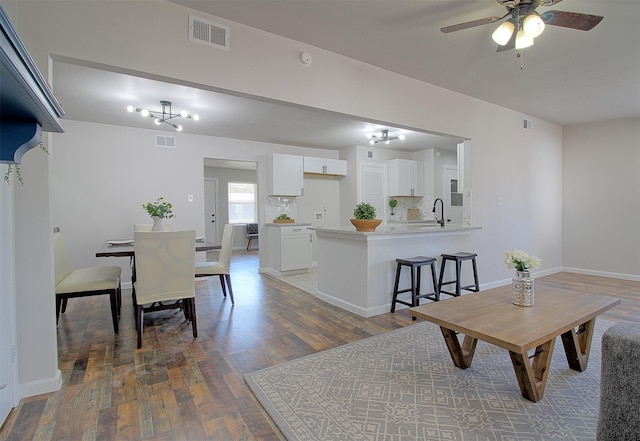 dining room with ceiling fan with notable chandelier, dark wood-type flooring, and sink