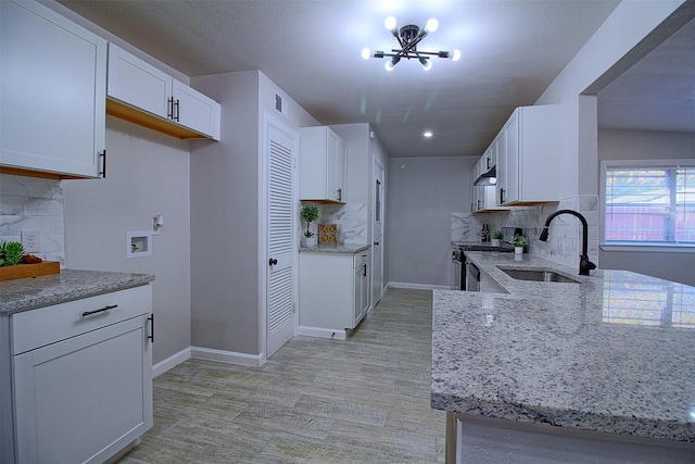 kitchen with sink, decorative backsplash, white cabinetry, and gas range