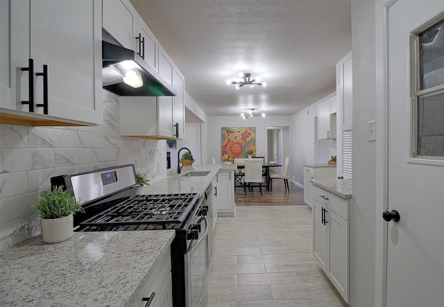 kitchen with an inviting chandelier, stainless steel range with gas cooktop, decorative backsplash, and white cabinetry