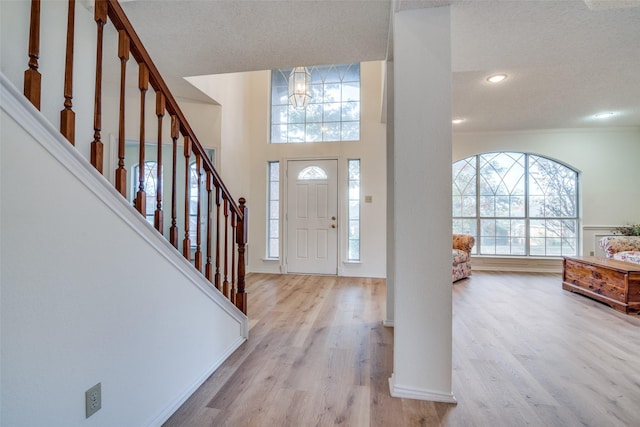 entrance foyer featuring an inviting chandelier, a textured ceiling, and light hardwood / wood-style floors