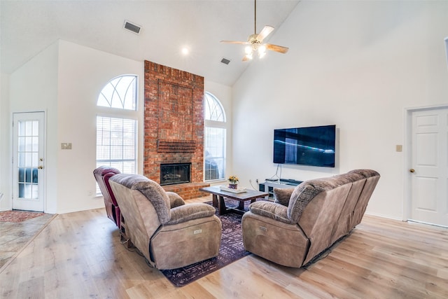 living room with ceiling fan, a fireplace, light hardwood / wood-style floors, and high vaulted ceiling