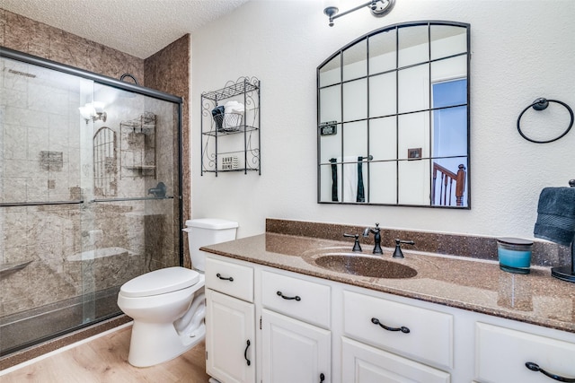 bathroom with toilet, wood-type flooring, a textured ceiling, vanity, and a shower with door