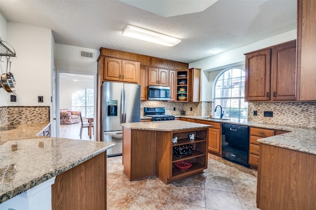 kitchen featuring appliances with stainless steel finishes, a wealth of natural light, light stone counters, and a textured ceiling