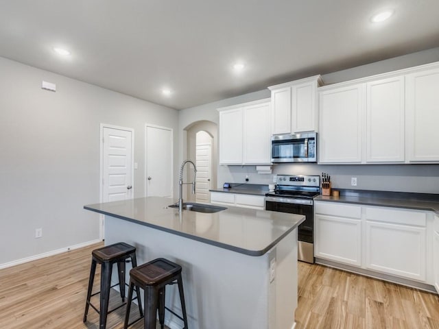 kitchen featuring stainless steel appliances, a center island with sink, white cabinets, and sink