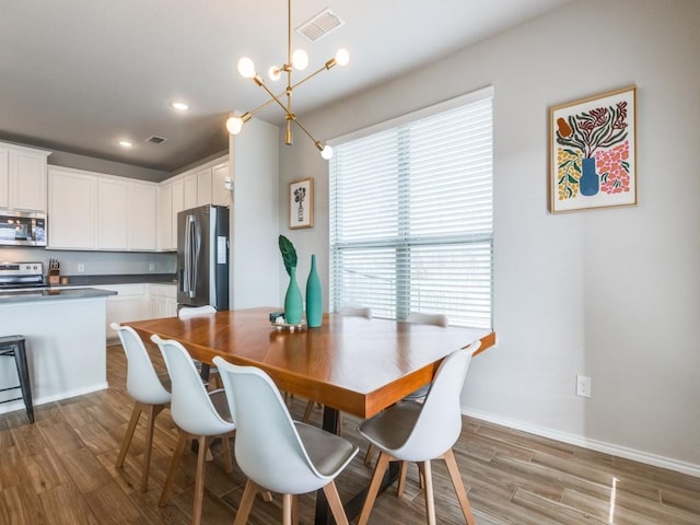 dining area with light wood-type flooring and a chandelier