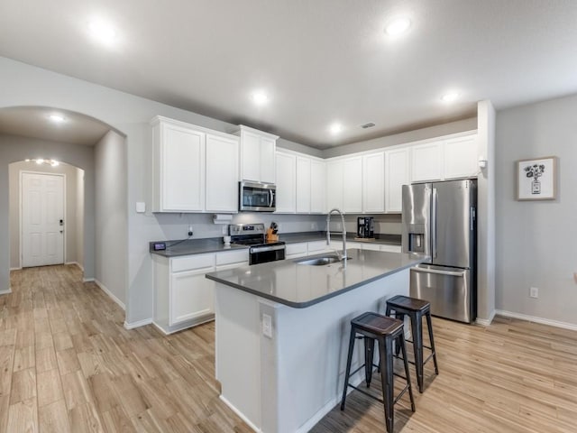 kitchen featuring appliances with stainless steel finishes, white cabinetry, a kitchen island with sink, and sink