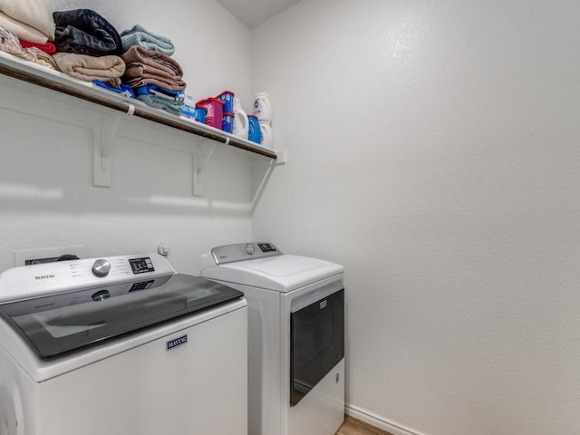 clothes washing area with washer and clothes dryer and hardwood / wood-style flooring