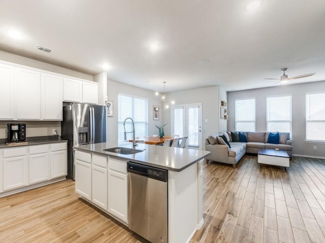 kitchen featuring stainless steel appliances, an island with sink, ceiling fan, sink, and white cabinetry