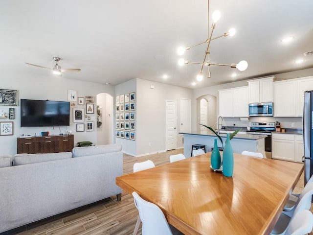 dining room featuring ceiling fan with notable chandelier and sink