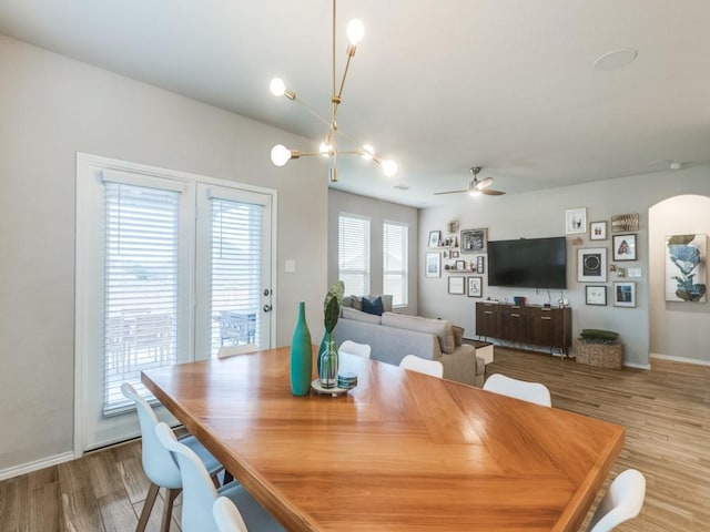 dining room featuring ceiling fan with notable chandelier and light hardwood / wood-style floors