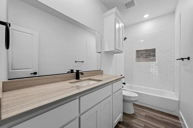 full bathroom with toilet, wood-type flooring, vanity, and tiled shower / bath