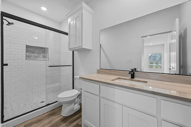 bathroom with hardwood / wood-style floors, an enclosed shower, vanity, and toilet