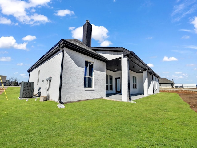 rear view of property featuring a patio, central AC, and a lawn