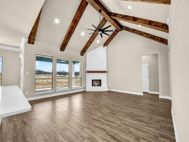 unfurnished living room featuring a large fireplace, high vaulted ceiling, beam ceiling, and ceiling fan