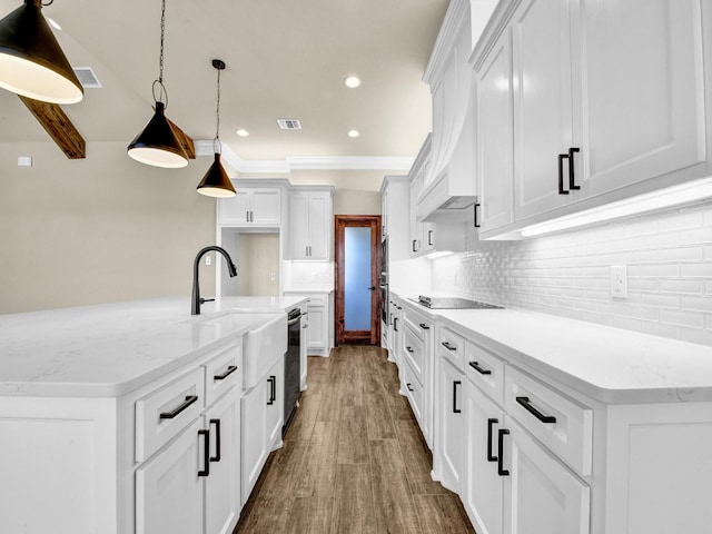 kitchen with a kitchen island with sink, black appliances, hanging light fixtures, light stone counters, and white cabinetry