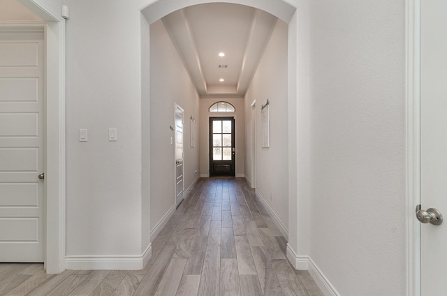 doorway featuring light hardwood / wood-style floors and a tray ceiling