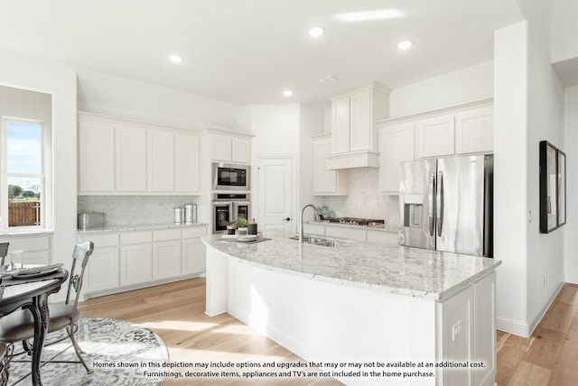 kitchen featuring stainless steel appliances, white cabinets, sink, and a kitchen island with sink