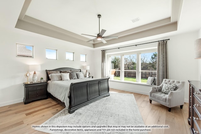 bedroom featuring light hardwood / wood-style floors, ceiling fan, and a tray ceiling