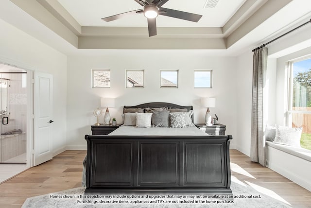 bedroom featuring ceiling fan, light hardwood / wood-style flooring, connected bathroom, and a tray ceiling