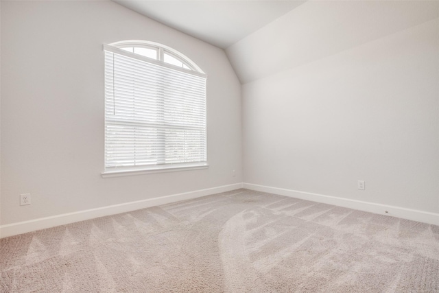 carpeted empty room featuring lofted ceiling