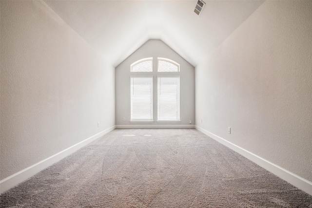 carpeted empty room featuring vaulted ceiling