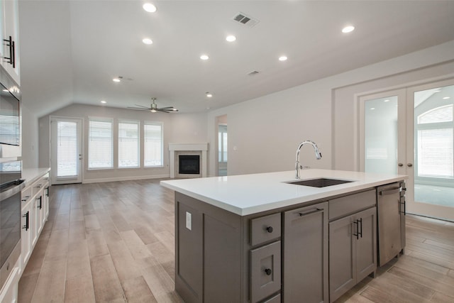 kitchen with stainless steel appliances, a kitchen island with sink, gray cabinetry, ceiling fan, and sink