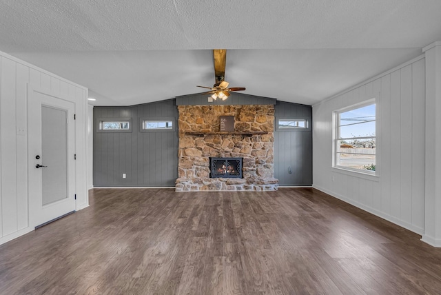 unfurnished living room featuring lofted ceiling with beams, ceiling fan, dark hardwood / wood-style flooring, wooden walls, and a fireplace