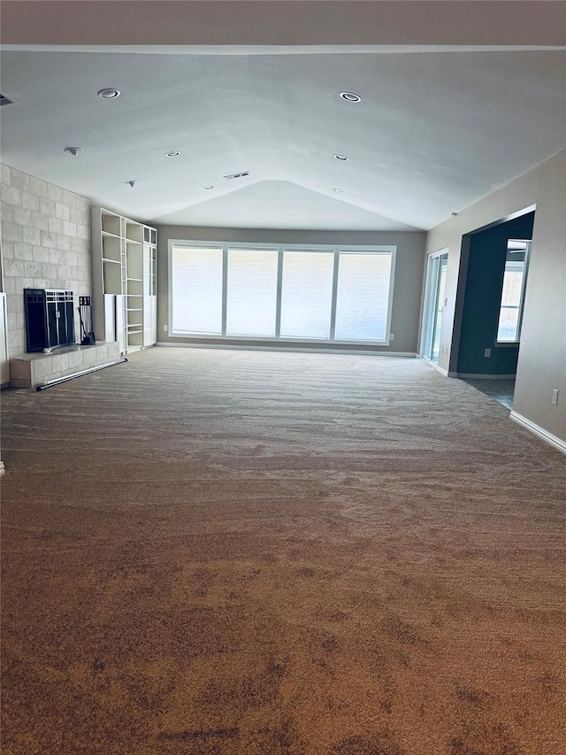 unfurnished living room featuring a large fireplace, vaulted ceiling, and carpet flooring