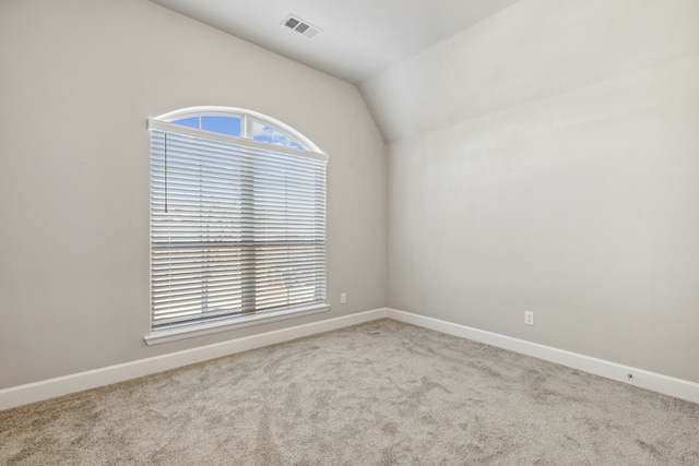 carpeted empty room with vaulted ceiling